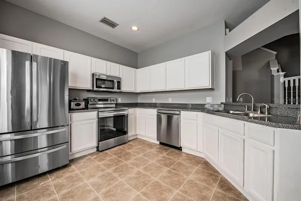 a kitchen with granite countertop a refrigerator stove and sink