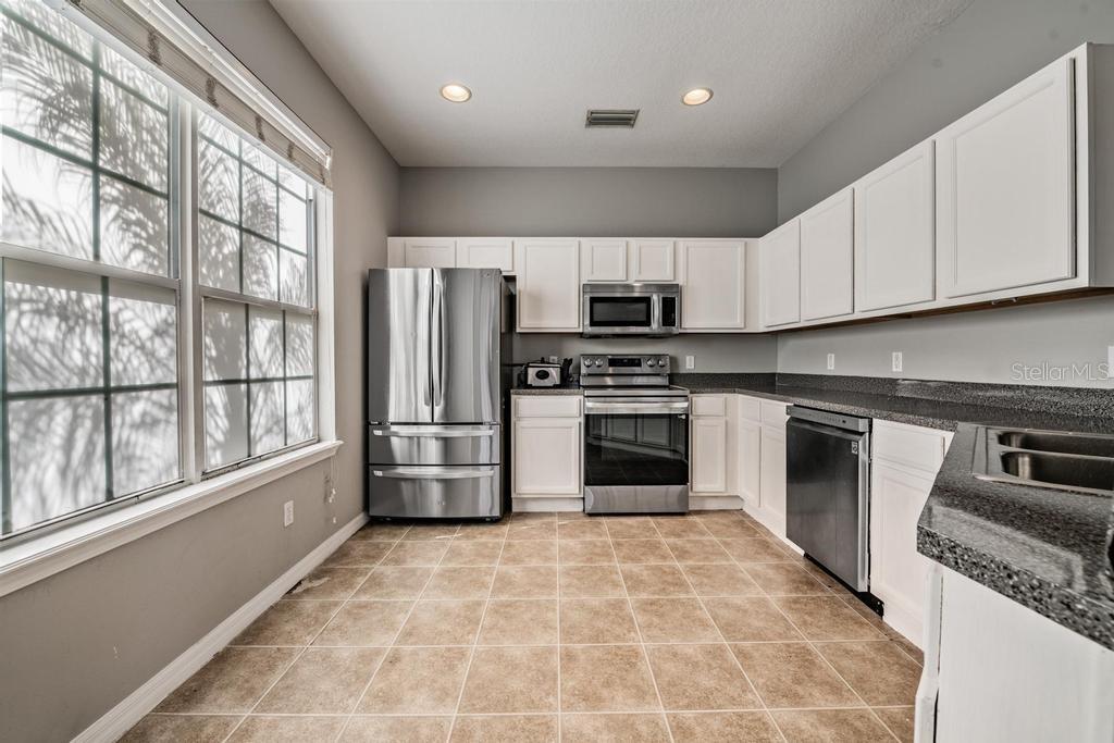 8512 Shallow Creek Court New Port Richey, FL 34653 - Photo 17 of 45 a kitchen with stainless steel appliances granite countertop a stove a sink and a refrigerator