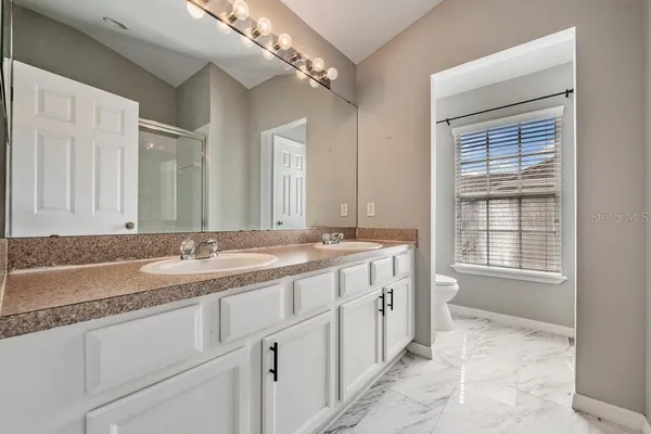 a bathroom with a granite countertop double vanity sink a mirror and a