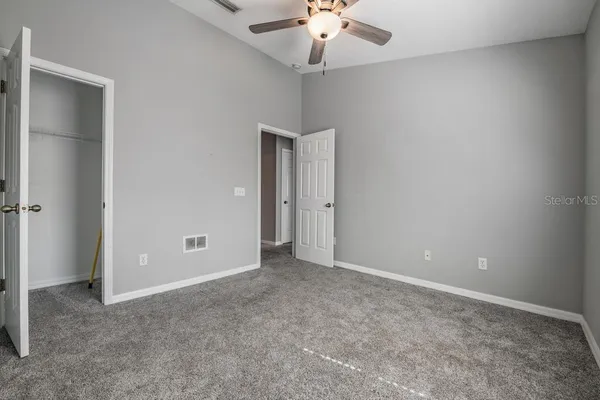 an empty room with a chandelier fan and closet