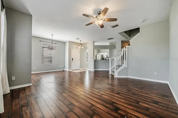 a view of an empty room with wooden floor and a ceiling fan