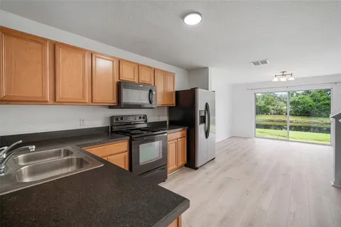 a kitchen with stainless steel appliances granite countertop a stove a sink and a refrigerator with cabinets