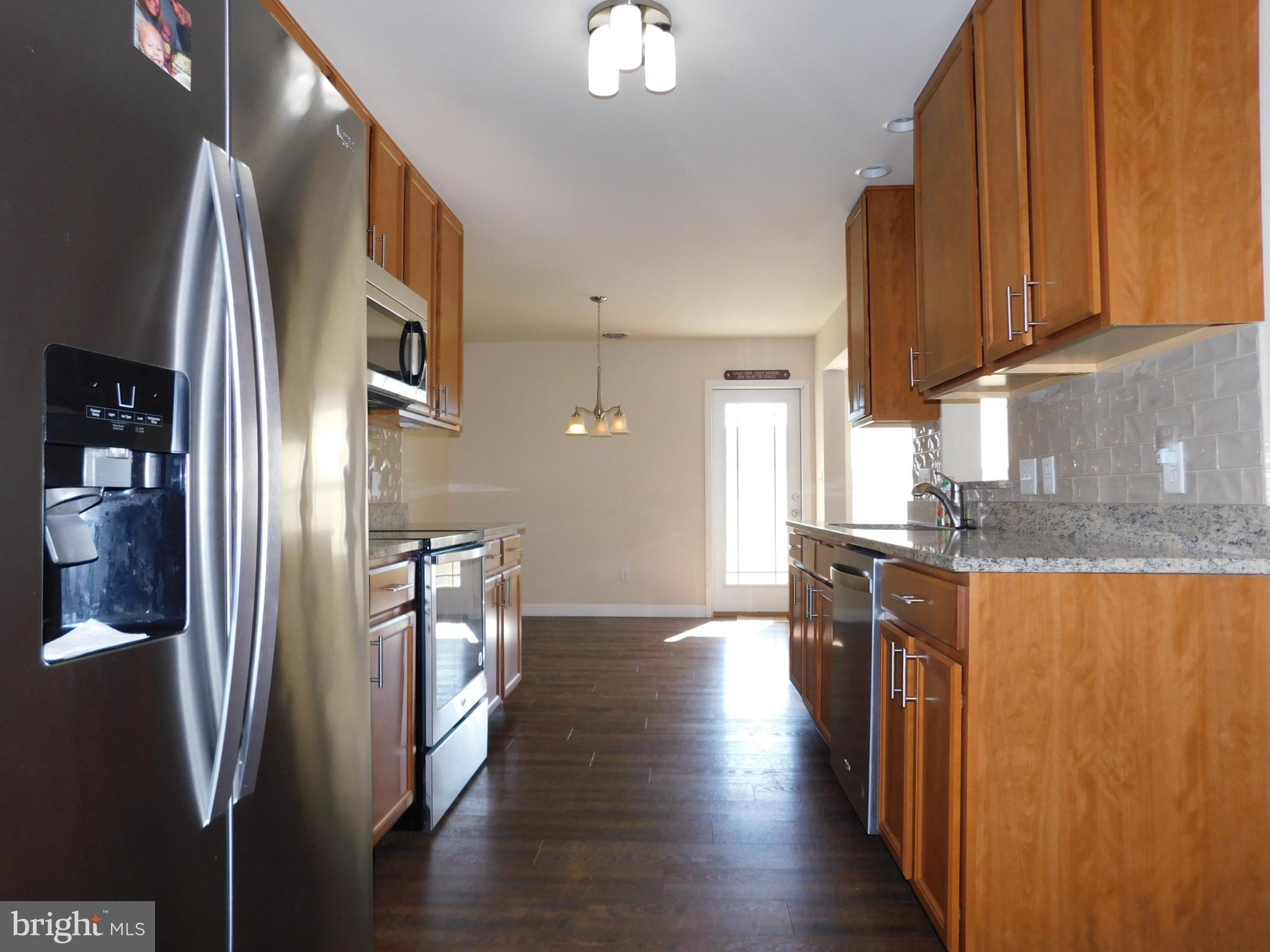 424 Eisenhower Drive Chambersburg, PA 17201 - Photo 7 of 30 a kitchen with stainless steel appliances granite countertop a refrigerator a stove and a sink with wooden floor