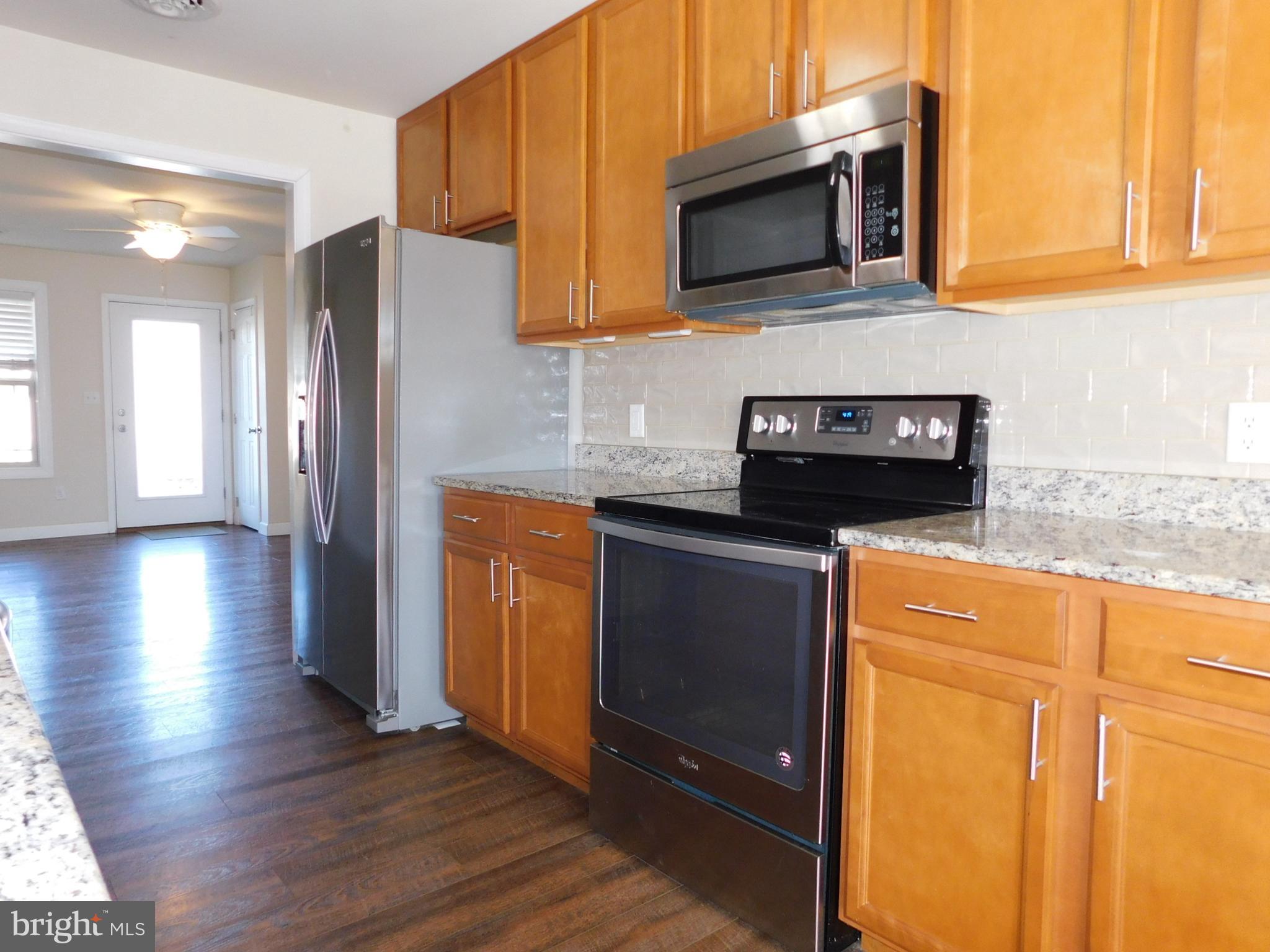 424 Eisenhower Drive Chambersburg, PA 17201 - Photo 10 of 30 a kitchen with granite countertop wooden cabinets stainless steel appliances and a wooden floor