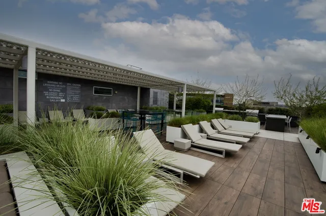 a view of a patio with couches potted plants and wooden floor