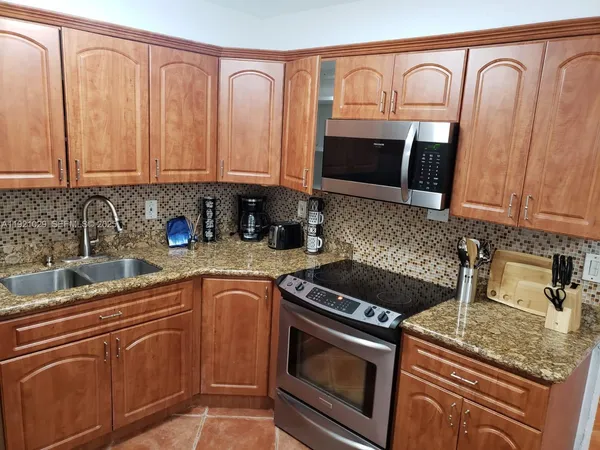 a kitchen with granite countertop a sink stove and cabinets