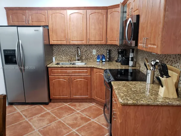 a kitchen with stainless steel appliances granite countertop a sink a microwave a refrigerator and white cabinets