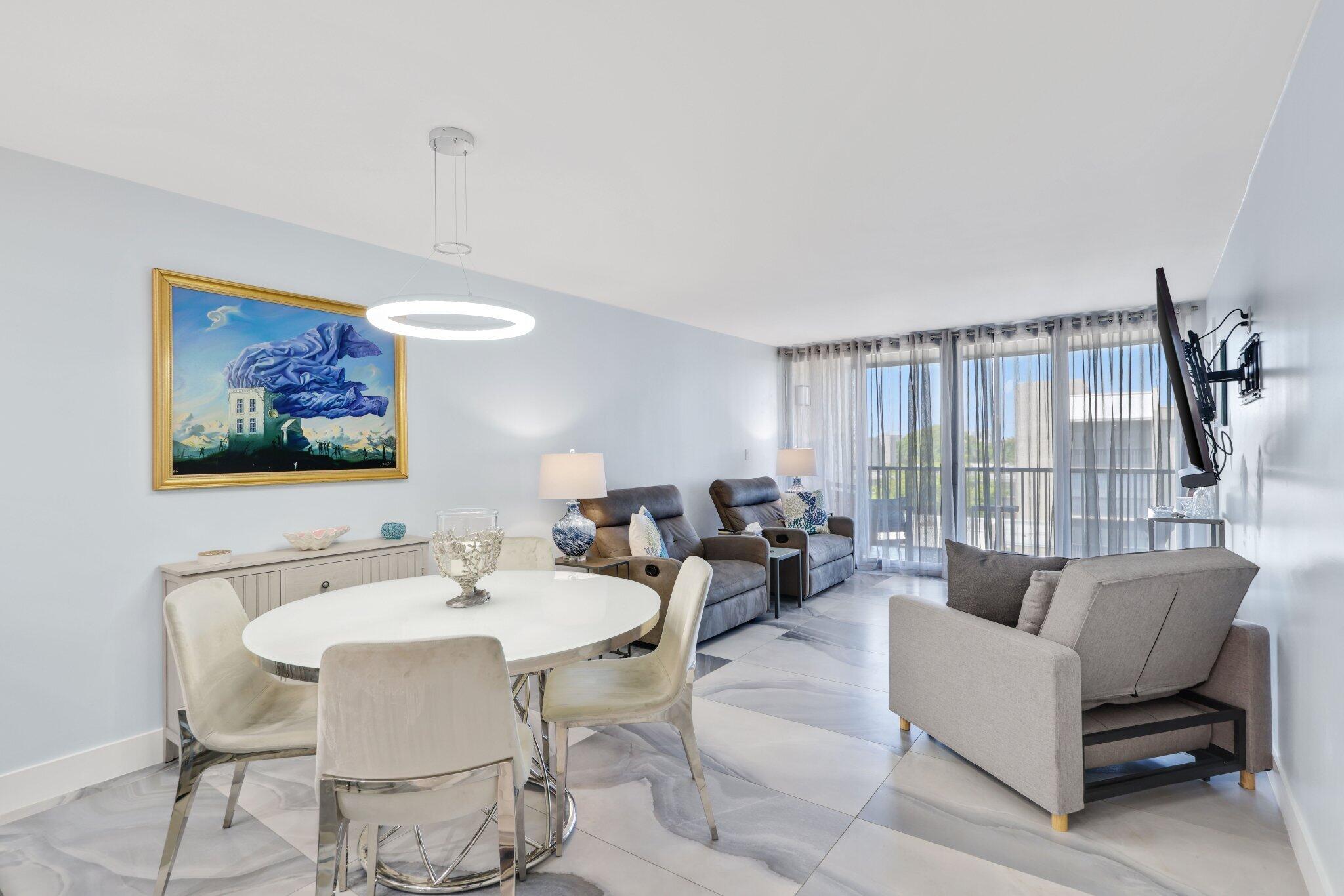 12 Royal Palm Way, Unit 605 Boca Raton, FL 33432 - Photo 14 of 47 a living room with furniture a large window and a dining table