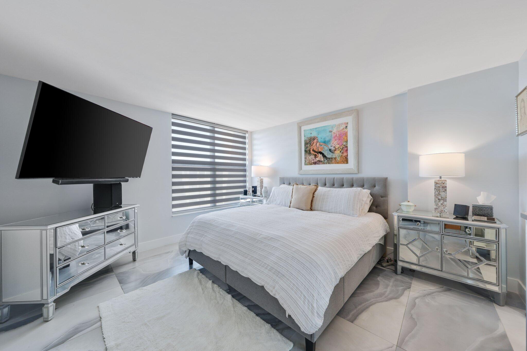 12 Royal Palm Way, Unit 605 Boca Raton, FL 33432 - Photo 22 of 47 a bedroom with a bed and a flat tv screen on the dresser