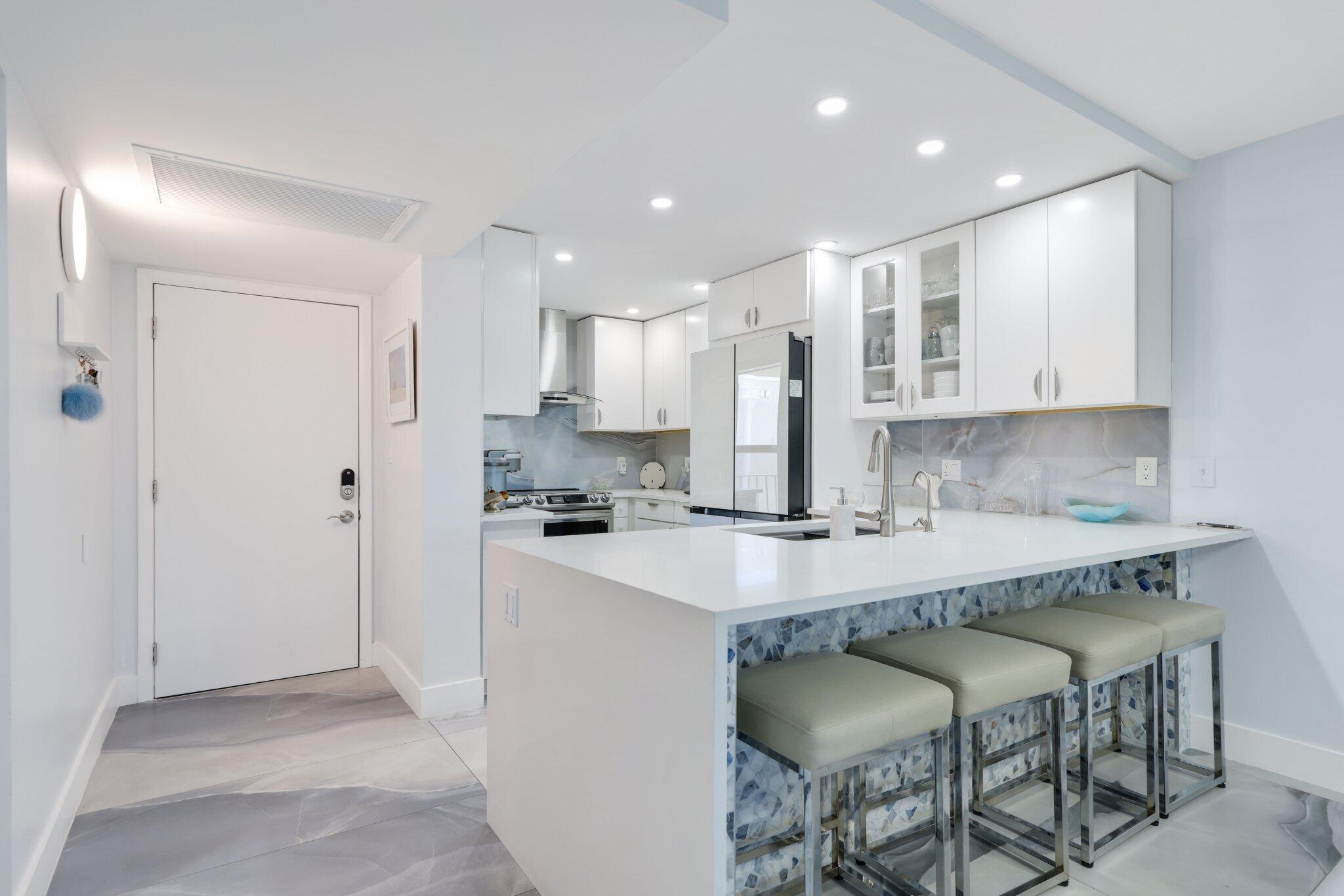 12 Royal Palm Way, Unit 605 Boca Raton, FL 33432 - Photo 9 of 47 a kitchen with stainless steel appliances granite countertop a table chairs sink and cabinets