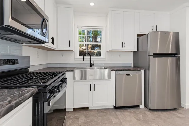 a kitchen with stainless steel appliances granite countertop a refrigerator a sink and a stove