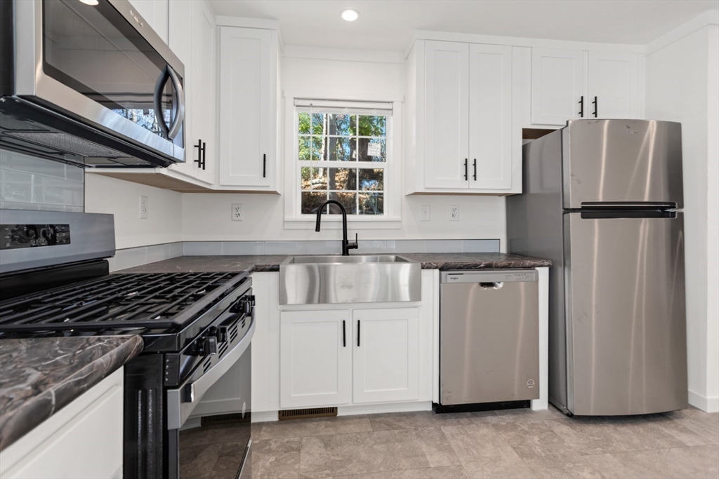 98 Newbury Street, Unit 4B Danvers, MA 01923 - Photo 13 of 32 a kitchen with stainless steel appliances granite countertop a refrigerator a sink and a stove