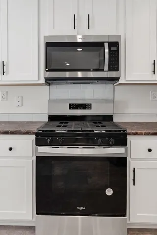 a kitchen with stainless steel appliances granite countertop white cabinets and black stove top oven with granite countertops