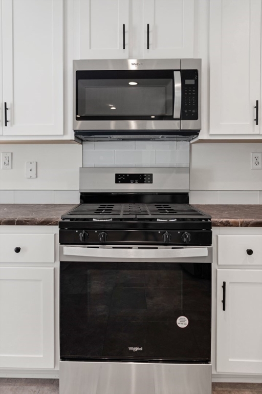 98 Newbury Street, Unit 4B Danvers, MA 01923 - Photo 18 of 32 a kitchen with stainless steel appliances granite countertop white cabinets and black stove top oven with granite countertops