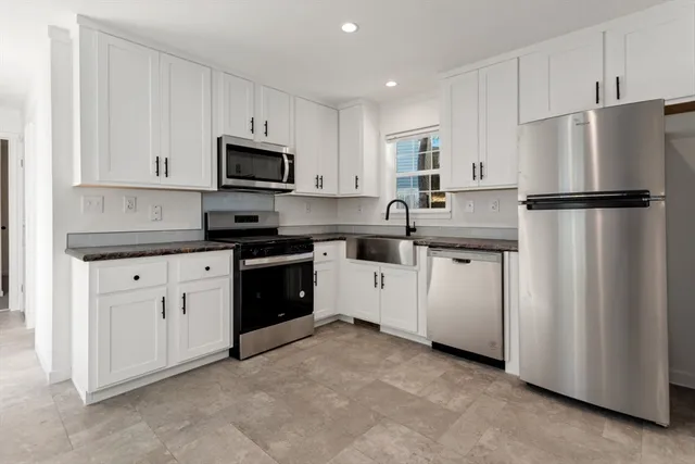 a kitchen with white cabinets and refrigerator