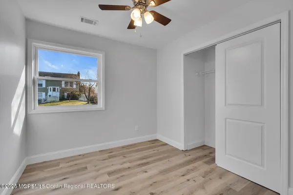 a view of empty room with wooden floor and fan