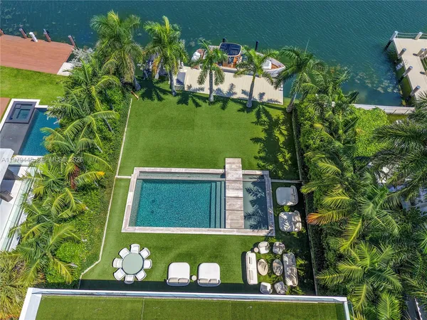 a view of a swimming pool with a lawn chairs under palm trees