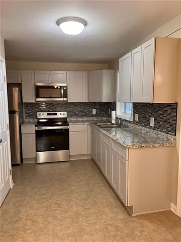 a kitchen with stainless steel appliances granite countertop a stove a sink and a microwave