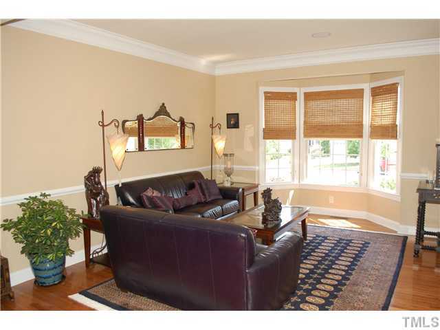 9140 Meadow Mist Court Raleigh, NC 27617 - Photo 3 of 25 Formal living room with hardwood floor, bay window, chair rail, and thick crown molding