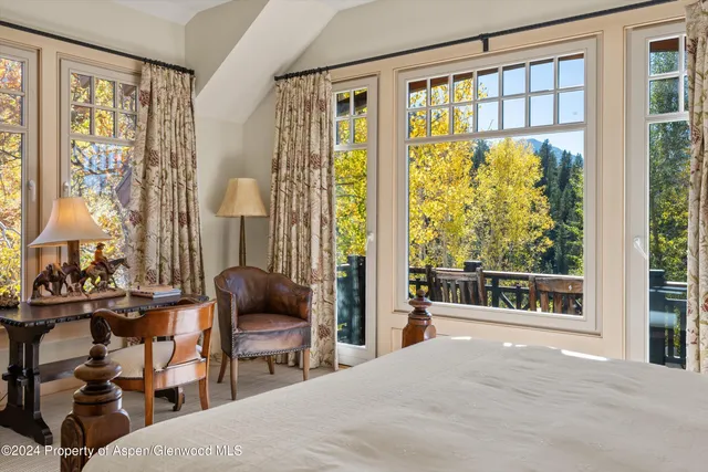 a bedroom with a bed and large windows