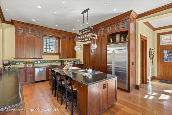 a kitchen with stainless steel appliances granite countertop a stove a sink dishwasher and a refrigerator with wooden floor