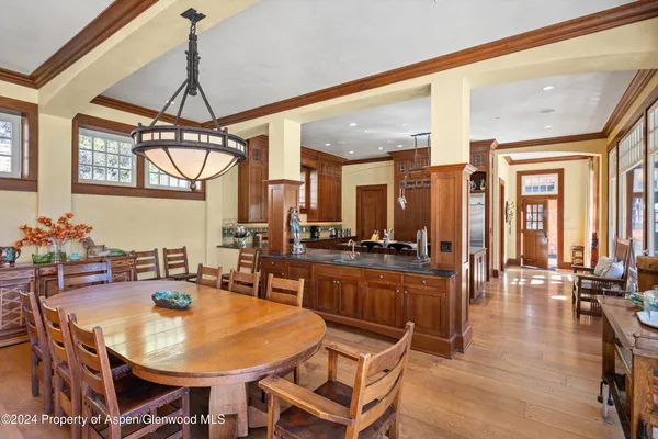 a dining room with wooden floor a chandelier a wooden table and chairs