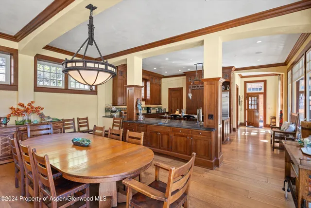 a dining room with wooden floor a chandelier a wooden table and chairs