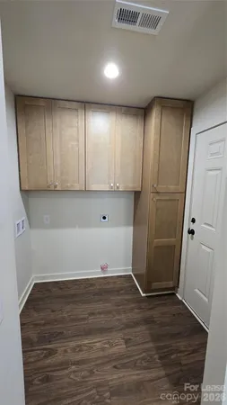 an empty room with wooden floor and cabinets