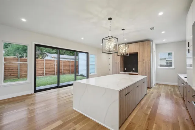 a kitchen with stainless steel appliances granite countertop a kitchen island hardwood floor sink stove dining table and chairs