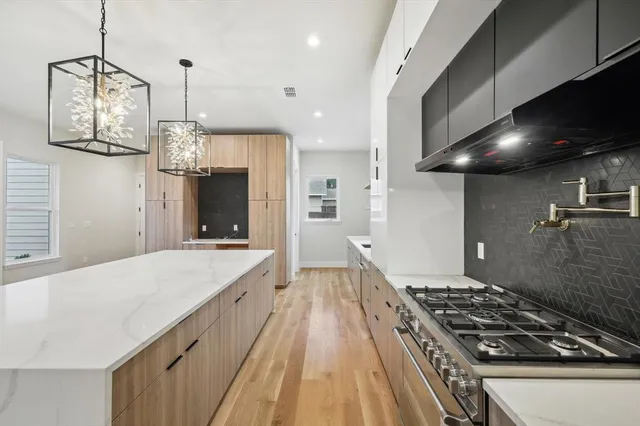 a large kitchen with kitchen island a large counter top a refrigerator and wooden floor