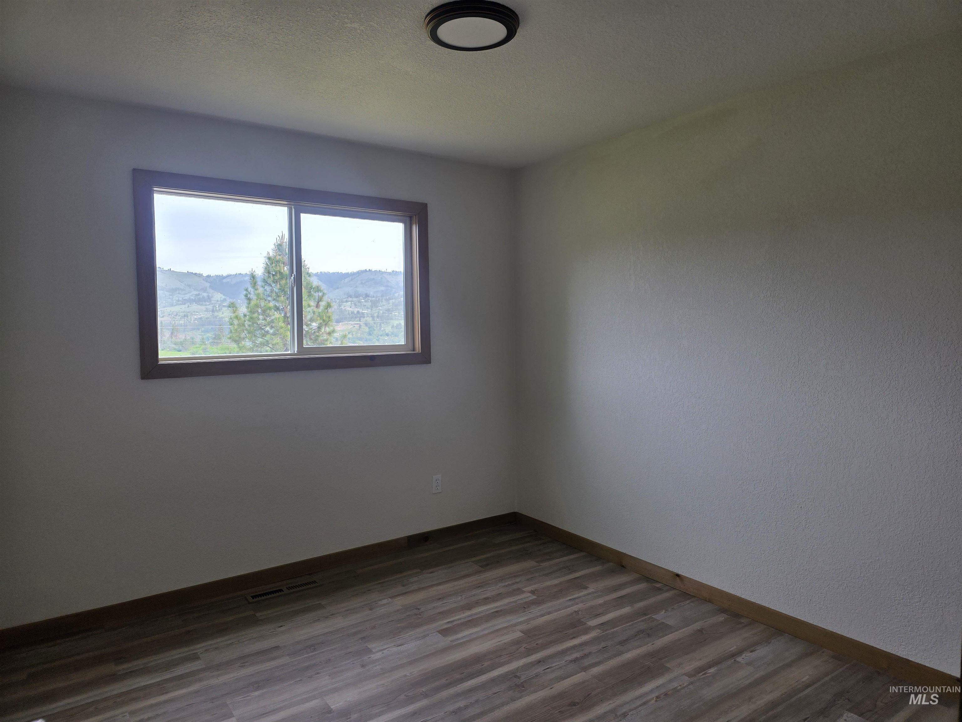 310 Fir Road Kamiah, ID 83536 - Photo 21 of 32 Interior room featuring wood-finish flooring, a window with wood trim, and a mountain and tree landscape