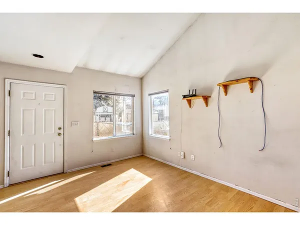 a view of an empty room with wooden floor and a window