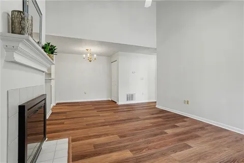 a view of an empty room with wooden floor and a fireplace