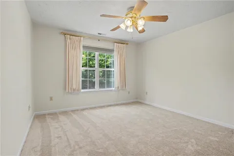 an empty room with a window and a fan