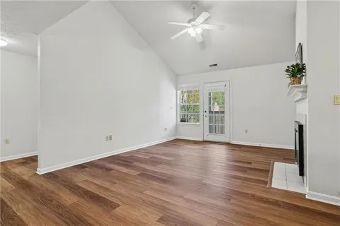 a view of an empty room with wooden floor and a window
