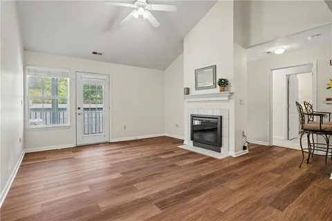 a view of an empty room with wooden floor fireplace and a window