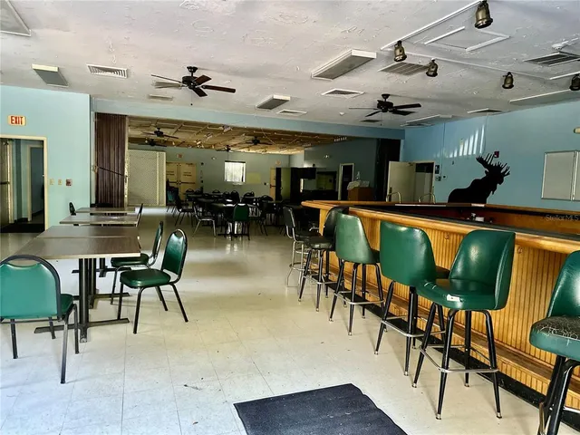 a dining hall with couches a dining table and chairs with wooden floor