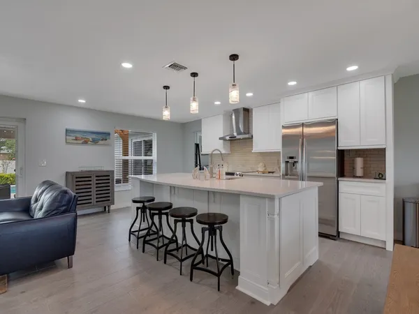 a kitchen with stainless steel appliances kitchen island granite countertop a sink and a refrigerator