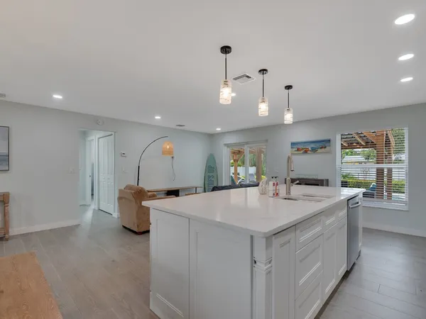 a large white kitchen with a sink and dishwasher a stove with wooden floor