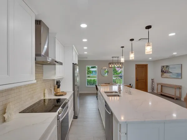a kitchen with a sink a refrigerator and chairs