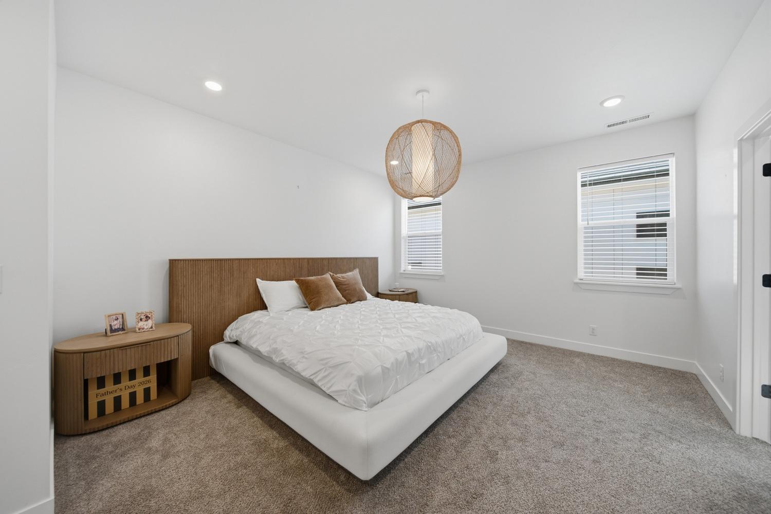6144 Red Sand Lane St. George, UT 84790 - Photo 6 of 19 The primary suite impresses with a woven wood headboard, matching nightstands, and a sculptural pendant light that adds a soft, organic focal point overhead. Plush carpeting, a generous footprint, and a large window bring warmth and daylight to this proportioned, retreat-caliber space.