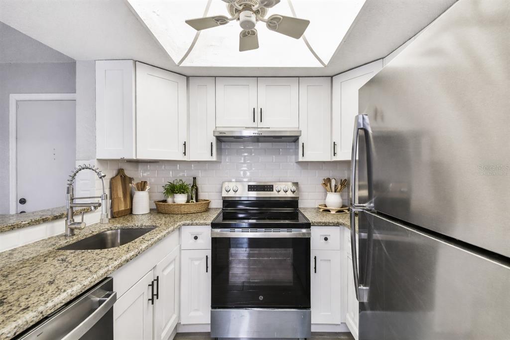 4726 Marine Parkway, Unit 103 New Port Richey, FL 34652 - Photo 4 of 81 a kitchen with stainless steel appliances granite countertop a sink stove and refrigerator