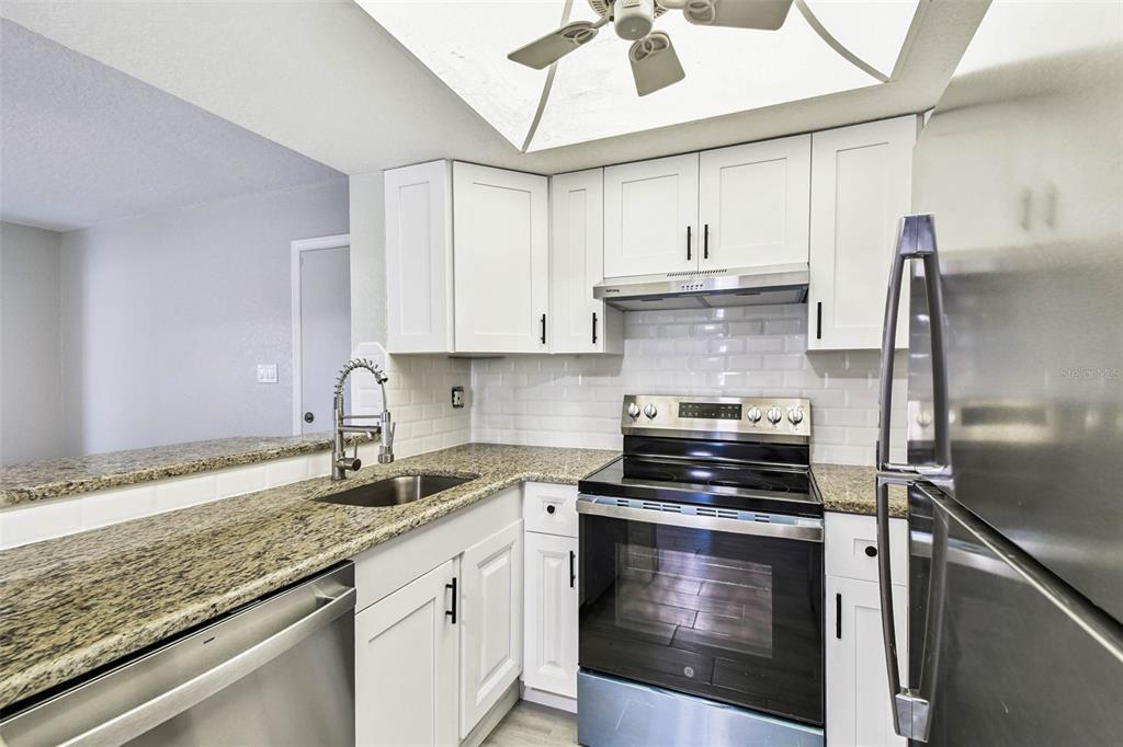 4726 Marine Parkway, Unit 103 New Port Richey, FL 34652 - Photo 8 of 81 a kitchen with granite countertop a sink stainless steel appliances and cabinets