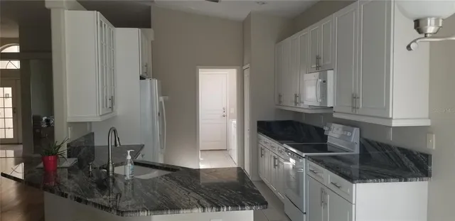 a kitchen with granite countertop a sink a stove and cabinets
