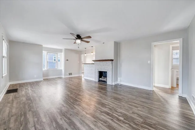 an empty room with wooden floor fireplace and windows