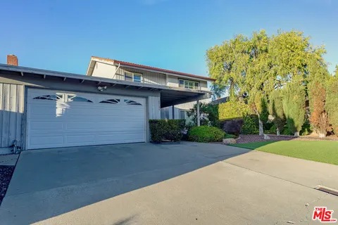 a front view of a house with a yard and potted plants