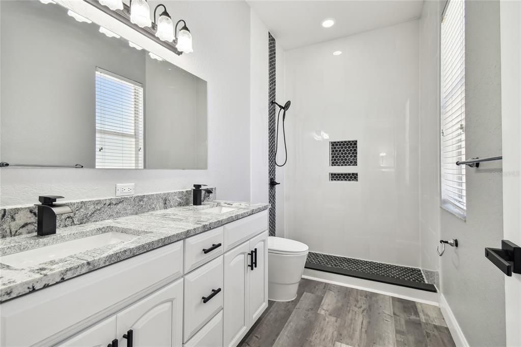 6644 Country Club Road Wesley Chapel, FL 33544 - Photo 52 of 75 a spacious bathroom with a granite countertop sink a toilet a mirror and shower