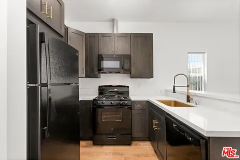 a kitchen with stainless steel appliances granite countertop a refrigerator a sink and a stove