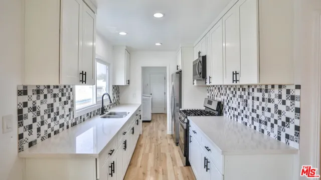 a large white kitchen with a sink and stainless steel appliances