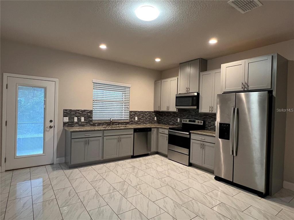 11 Ullock Place, Unit A Palm Coast, FL 32164 - Photo 2 of 10 a kitchen with granite countertop a refrigerator and a stove top oven